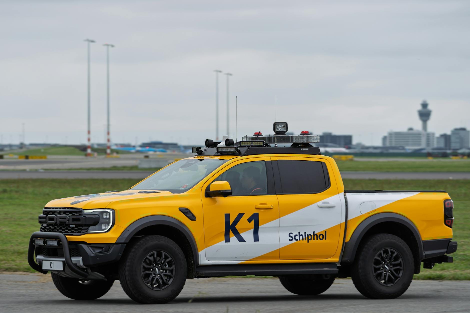 Żółty pojazd serwisowy na płycie lotniska Schiphol w Amsterdamie