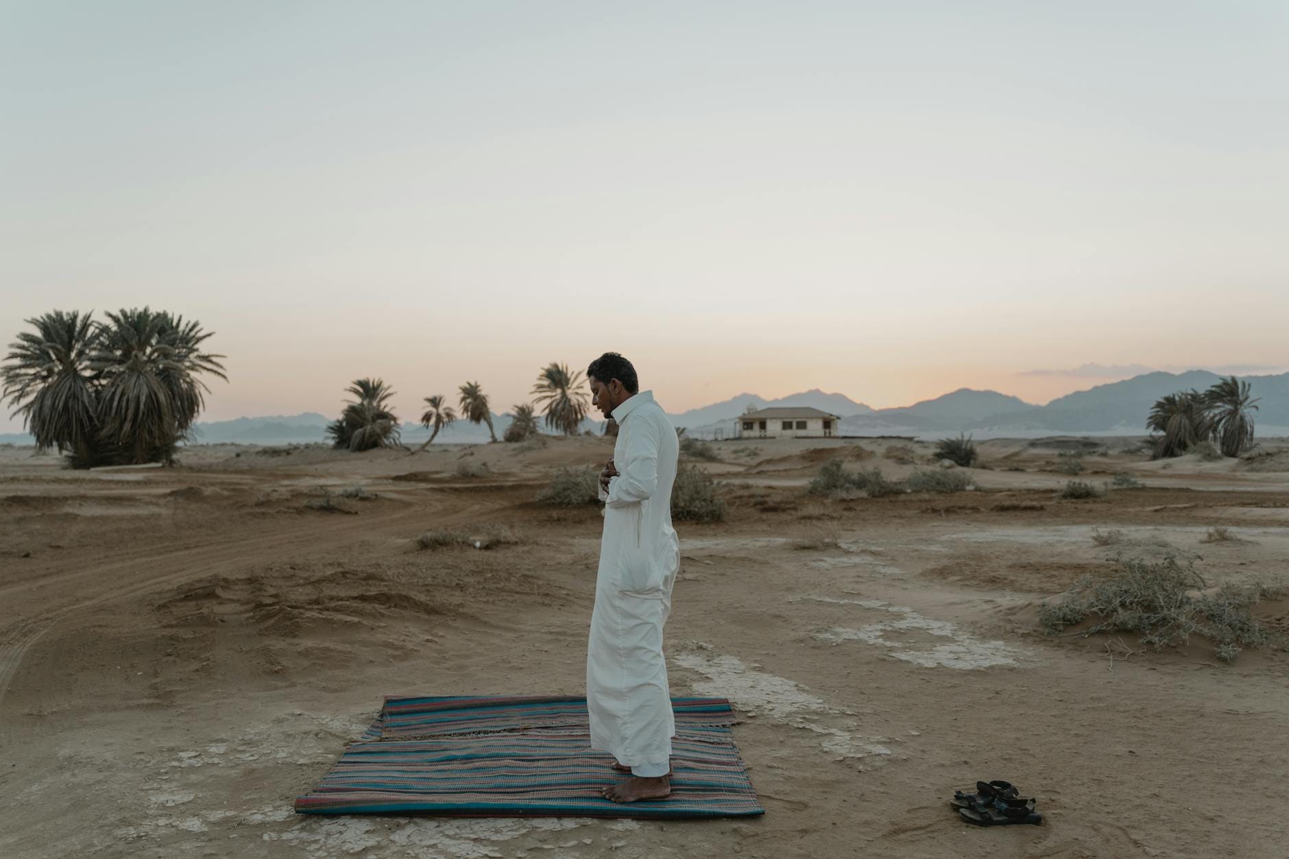 Mężczyzna modlący się o wschodzie słońca na pustyni