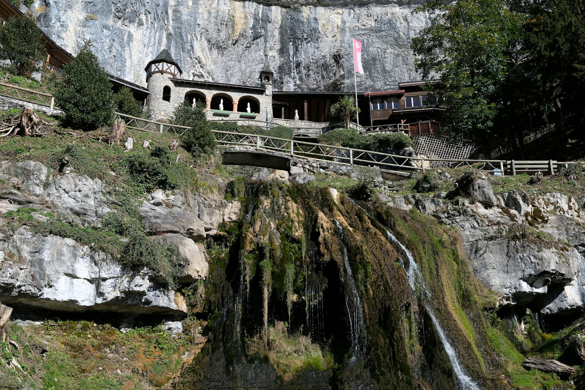 Wysoki wodospad spływający po skałach przy wejściu do jaskini