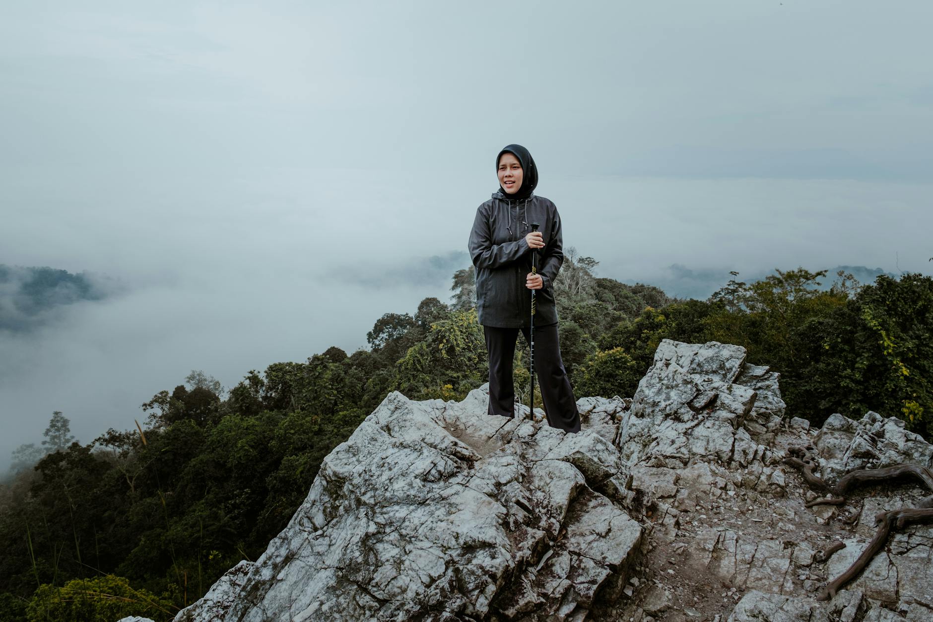Kobieta na skalistym szczycie wśród mglistych wzgórz w Malezji