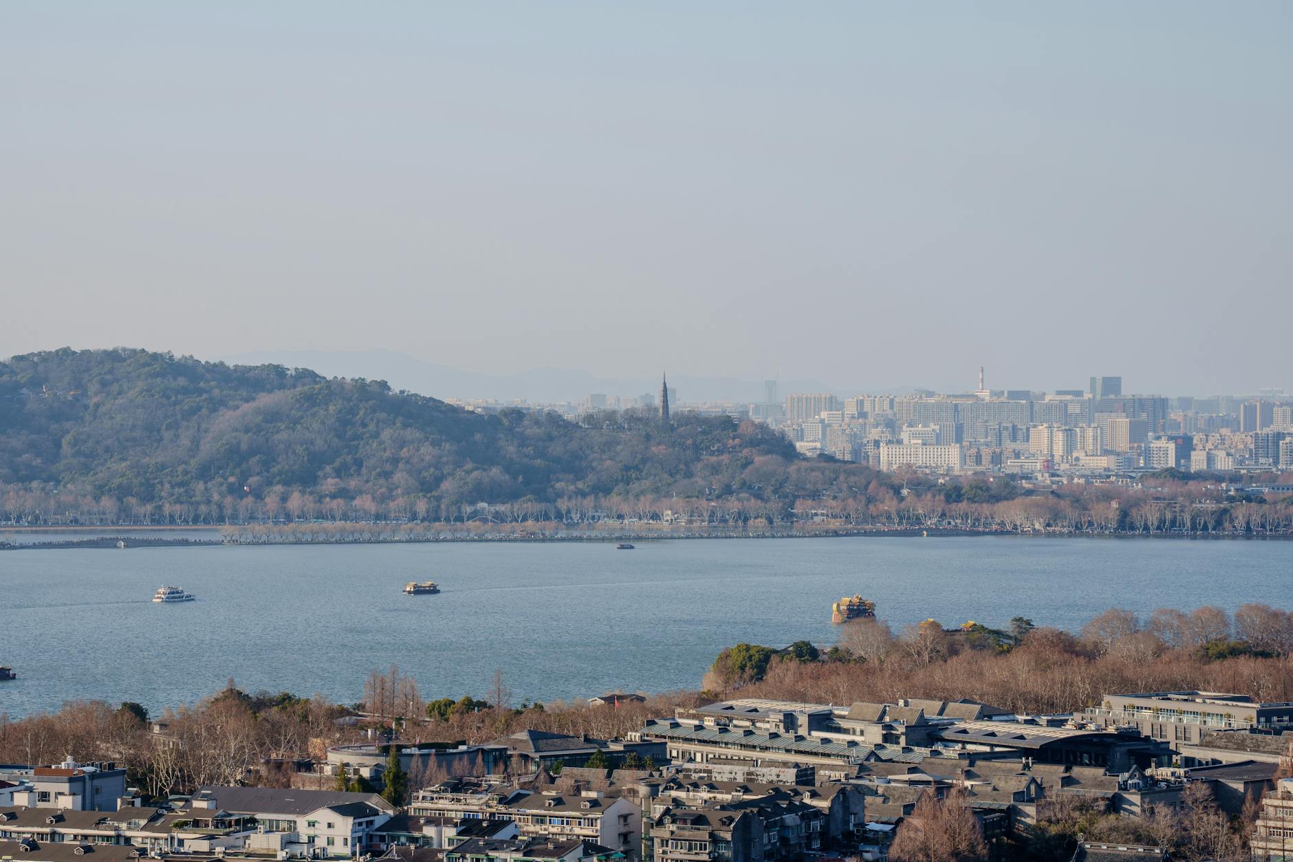 West Lake w Hangzhou z łódkami i panoramą miasta w słoneczny dzień